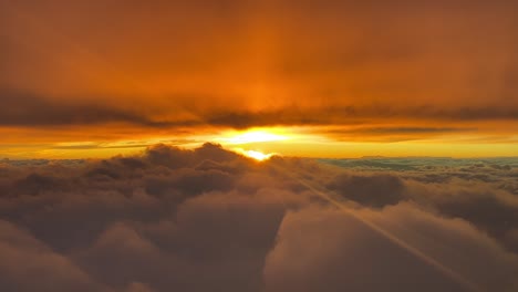 breathtaking red and orange sunset as seen by the pilots of an airplane flying westbound at 10000m high over the clouds with the sun ahead