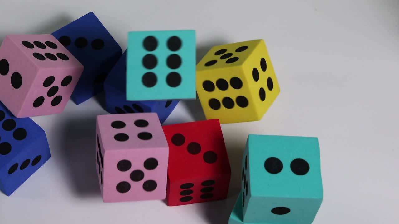 Colorful dice in motion, showcasing various numbers and hues against a plain background.