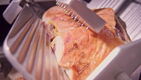 close up footage of prosciutto on a steel slicer dolly shot