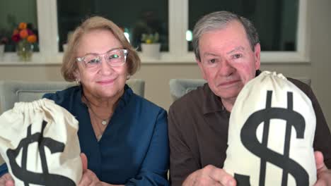 senior citizen couple slams bags of cash onto the table, female smiles and the man has a serious look