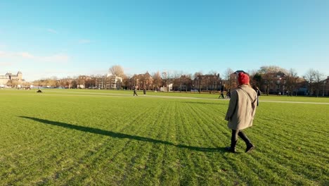 carefree girl walking alone in a green grass field and park on sunny winter day