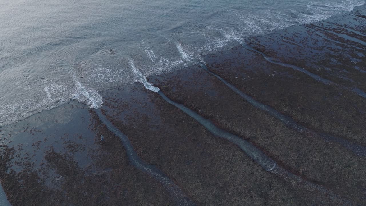 Panning Drone shot of Bingin Beach low tide reef at sunset in Uluwatu Bali Indonesia