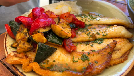 Tasty-fried-fish-with-vegetables-and-white-rice-on-a-plate,-traditional-Spanish-food-in-Spain,-4K-shot