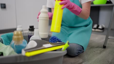 close up a girl cleaning lady in a blue apron transfers items for cleaning detergent into a gray plastic bowl and selects them while cleaning