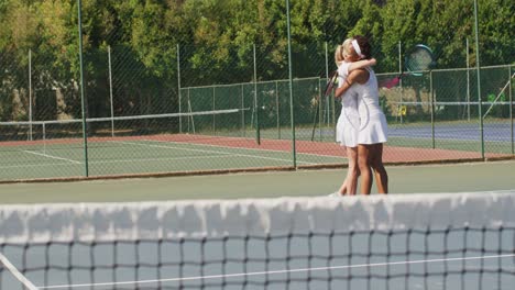 Video-of-happy-diverse-female-tennis-players-holding-rackets-and-embracing