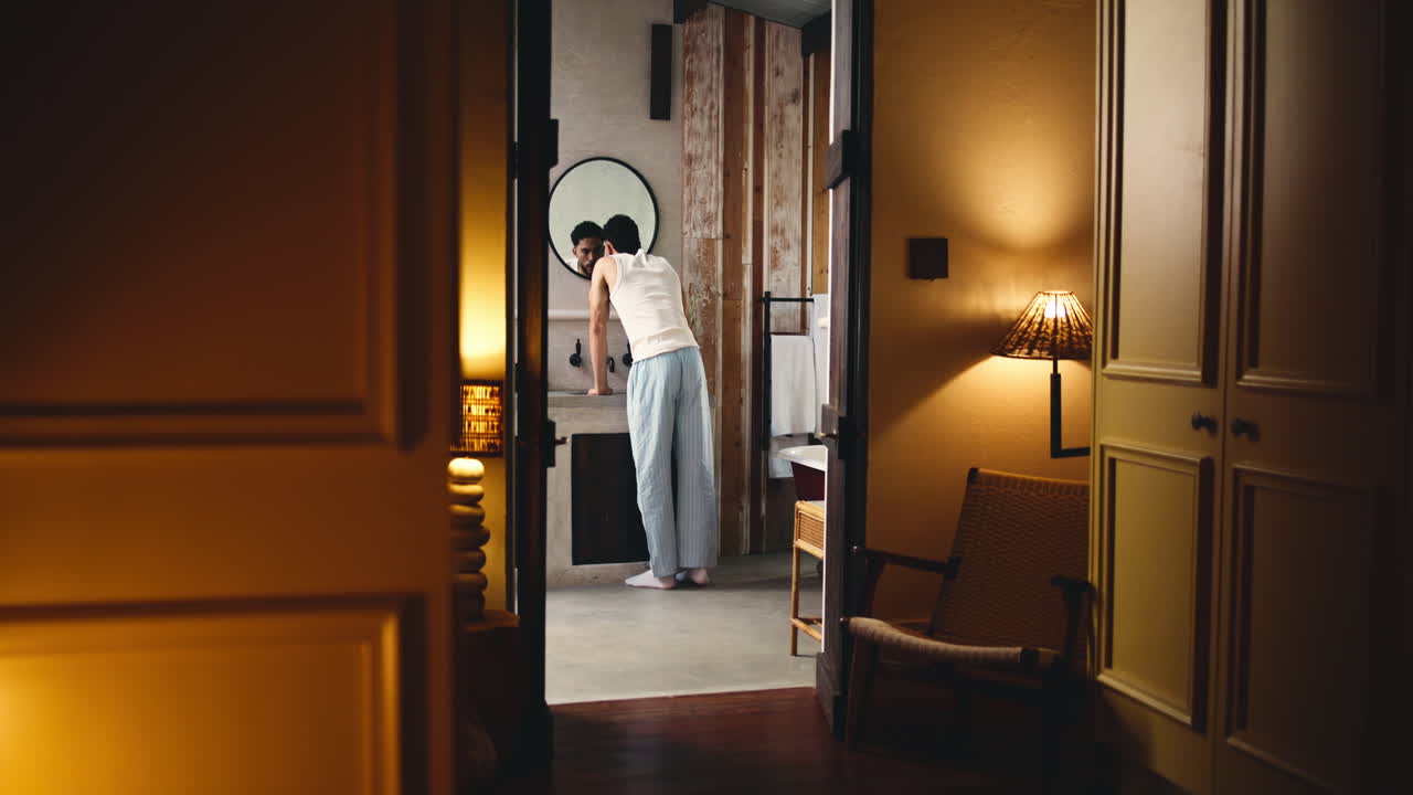 Uomo che si sveglia e si lava la faccia davanti allo specchio del bagno.