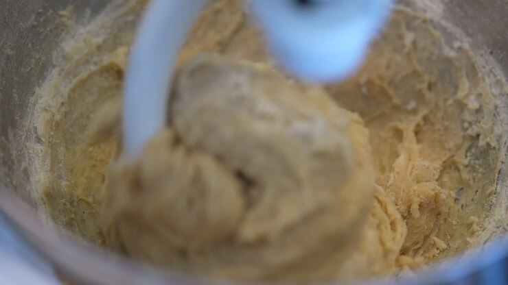 Straight down close up view of dough being mixed with a dough hook - slow motion macro view