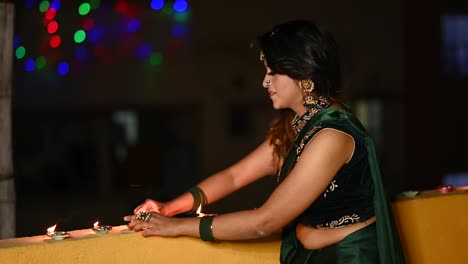 beautiful young woman lighting diya - oil lamp in traditional clothing on the occasion of diwali.