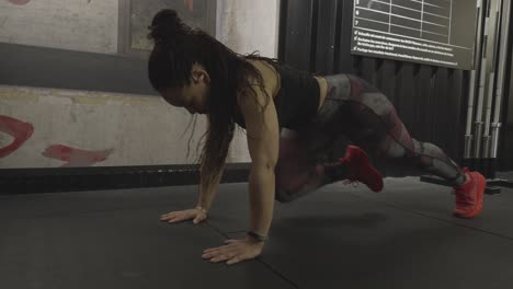 woman performs fast mountain climbers on gym floor as camera pans slightly from side to profile