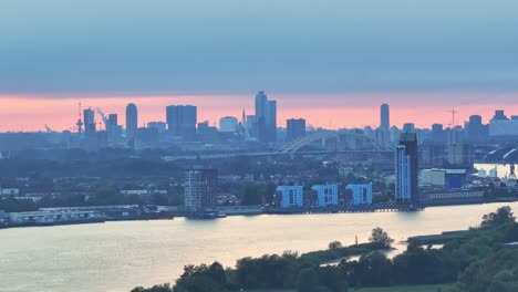 terwijl de oranje zon in de verte opkomt, wordt de stad rotterdam wakker.