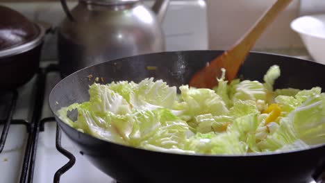 stir-frying fresh hakusai with other vegetables in a wok