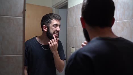 man checking his teeth and gums in front of mirror