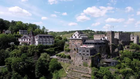 Aerial-flying-drone-shot,-tracking-right,-of-the-Rhine-River-Valley-and-Old-Architecture---including-medieval-castles,-old-buildings,-and-natural-forested-alpine-hills