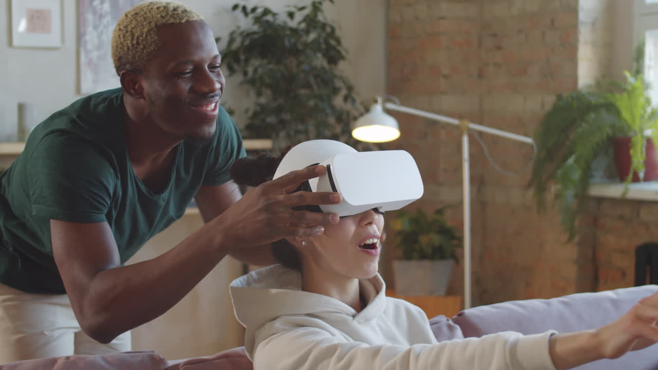 Begejstret kvinde bruger VR-headset med hjælp fra sin mand