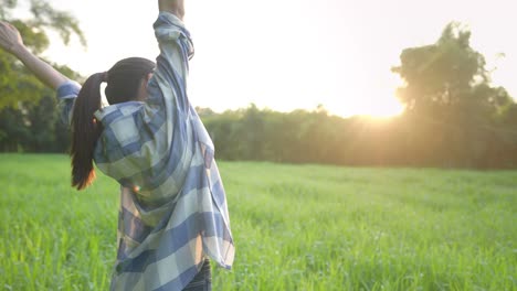 wake up fresh with morning light, asian female stretching her arms out welcoming a beautiful sunrise light to start the day, summer outdoor grass field, countryside relaxing vibe, farmer girl refresh