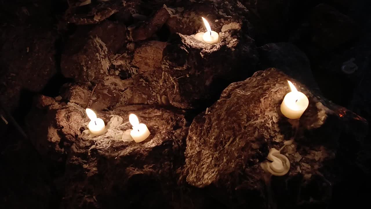 disparo en cámara lenta de pequeñas velas de luz de té parpadeando en una cueva oscura