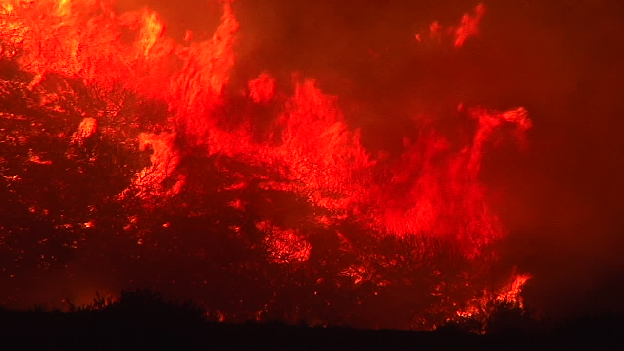토마스 파이어 인페르노는 밤에 캘리포니아 벤추라와 산타바바라 근처의 101번 고속도로 위의 풀밭에서 타오릅니다.