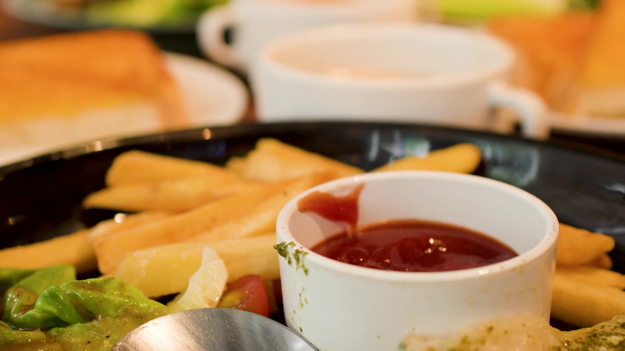Un primo piano si concentra su patatine fritte, ketchup e insalata durante un pasto al ristorante
