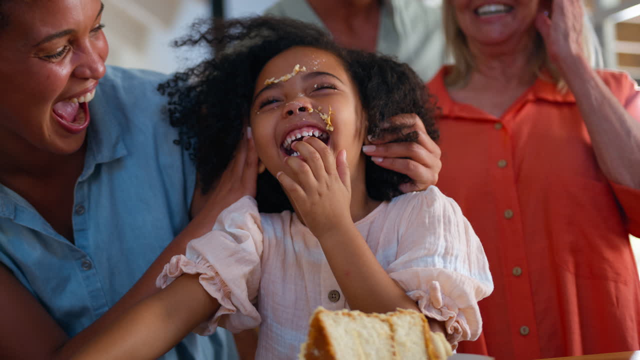 Nipote che fa disordine con la torta mentre una famiglia multigenerazionale festeggia il compleanno a casa
