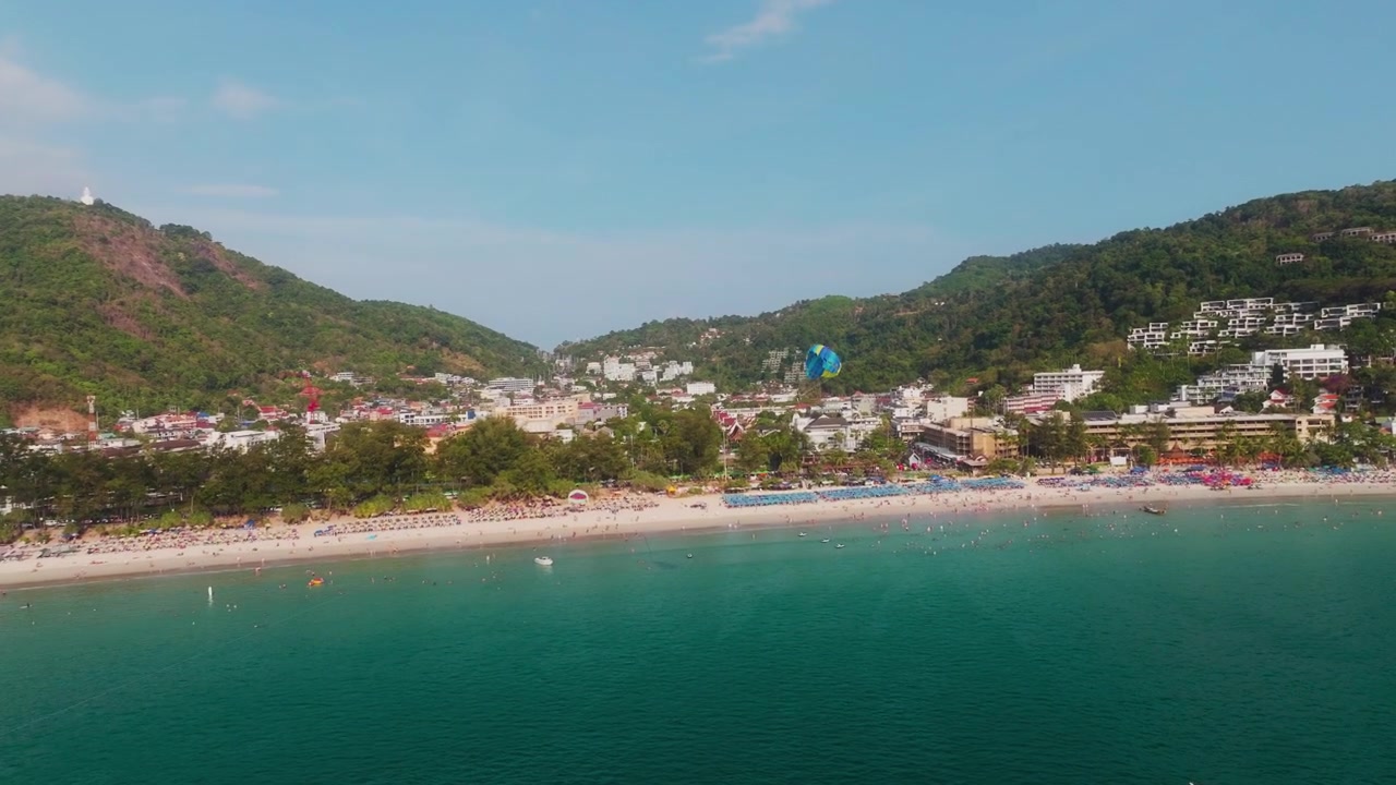 Drone svever over turkist hav mens en paraseil stiger over ikoniske Patong Beach