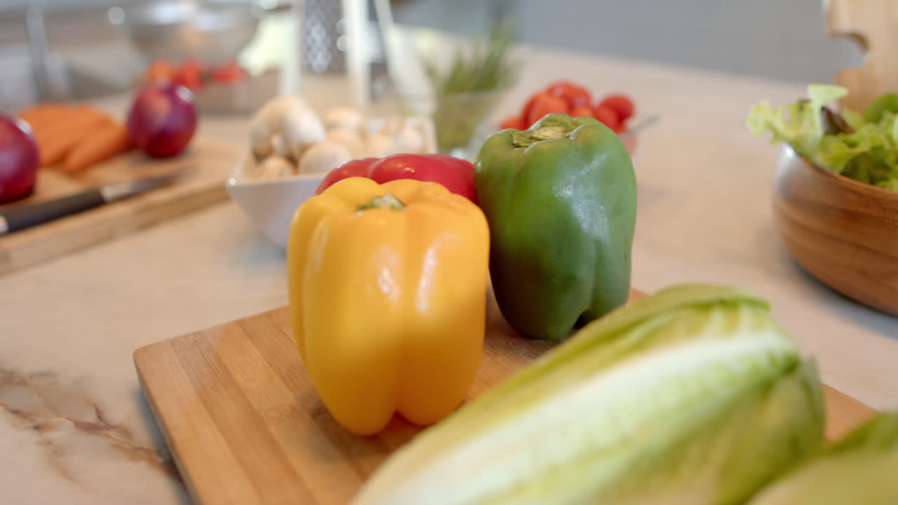 Colorful bell peppers and fresh vegetables on cutting board in kitchen