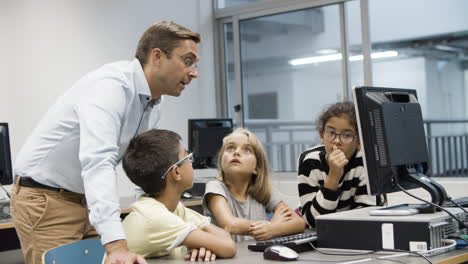 computer science teacher discussing task with schoolchildren