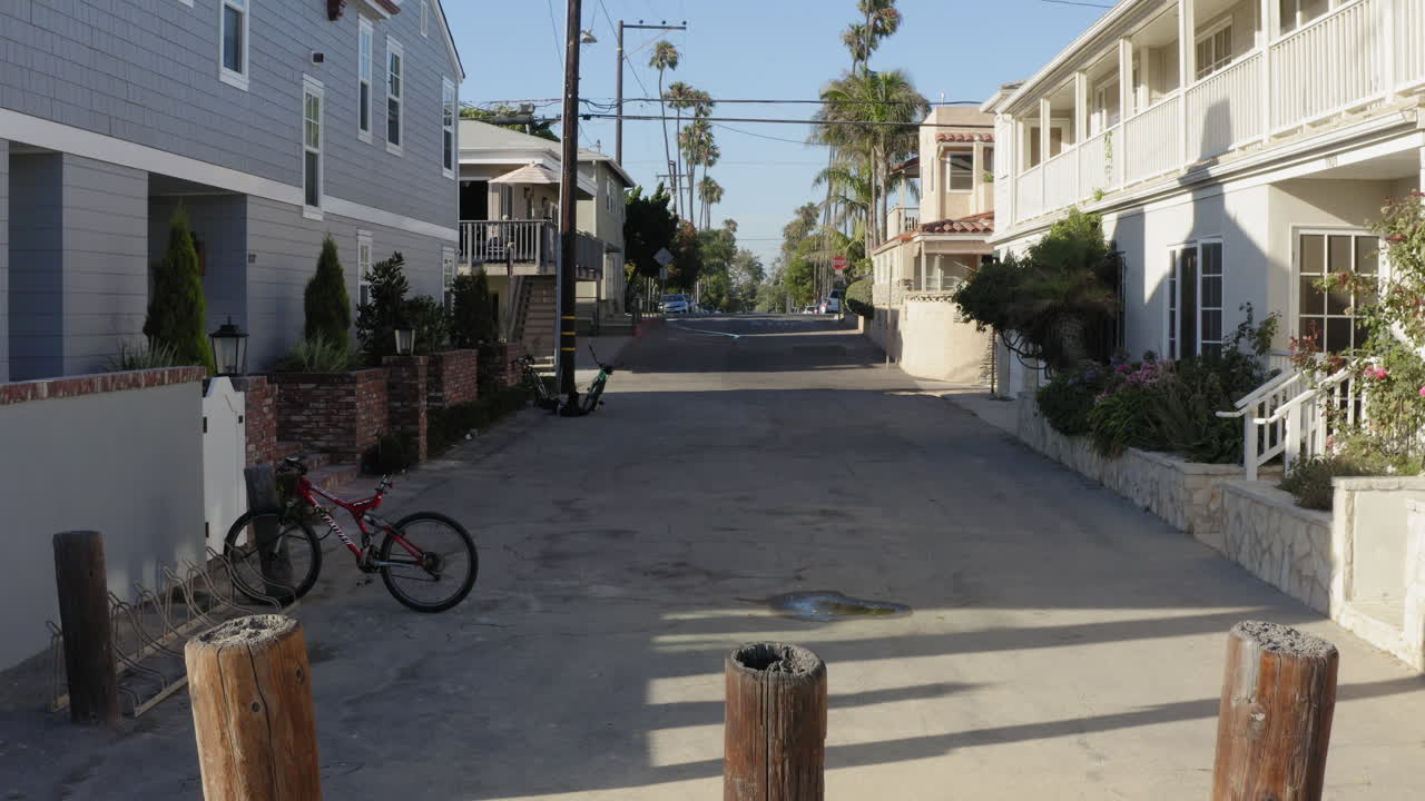 Iconic Los Angeles coastal houses with youngster skating by, drone fly forward