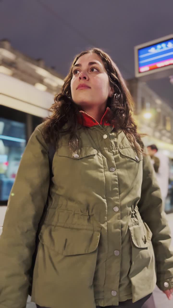 Donna che cammina di notte alla fermata dell'autobus.
