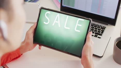 Caucasian-woman-at-desk-using-tablet,-online-shopping-during-sale,-slow-motion