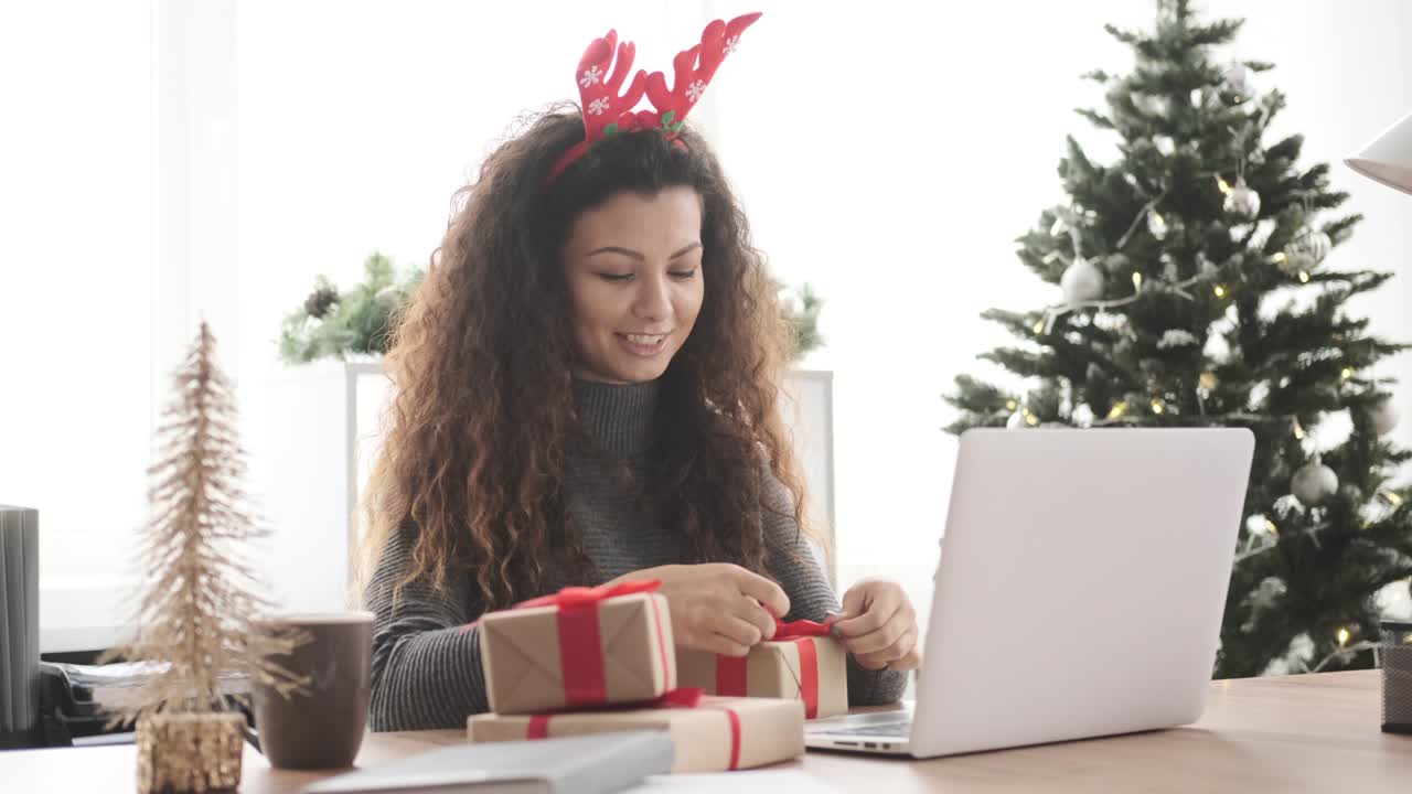 Happy woman wrapping Christmas gift at office