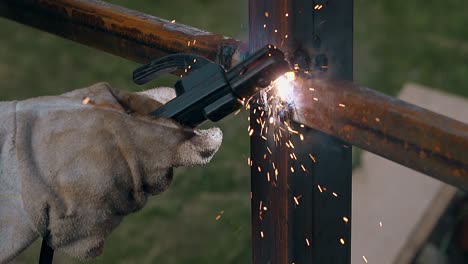 closeup worker hand with welding machine fixes fence