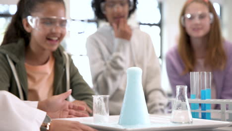 multiracial students in science class observing exciting chemical reaction, at school