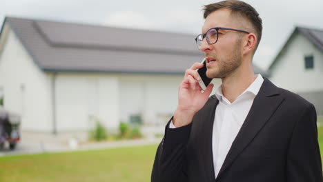 real estate agent on phone against new house for sale