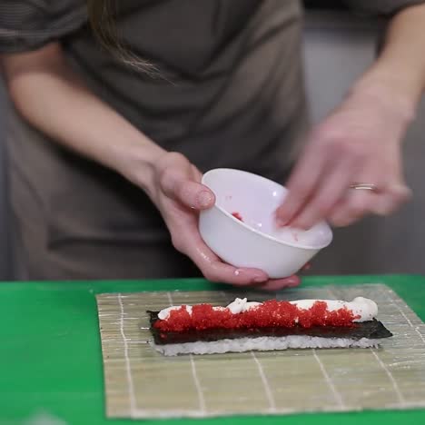 mujer chef llenando rollos de sushi japoneses