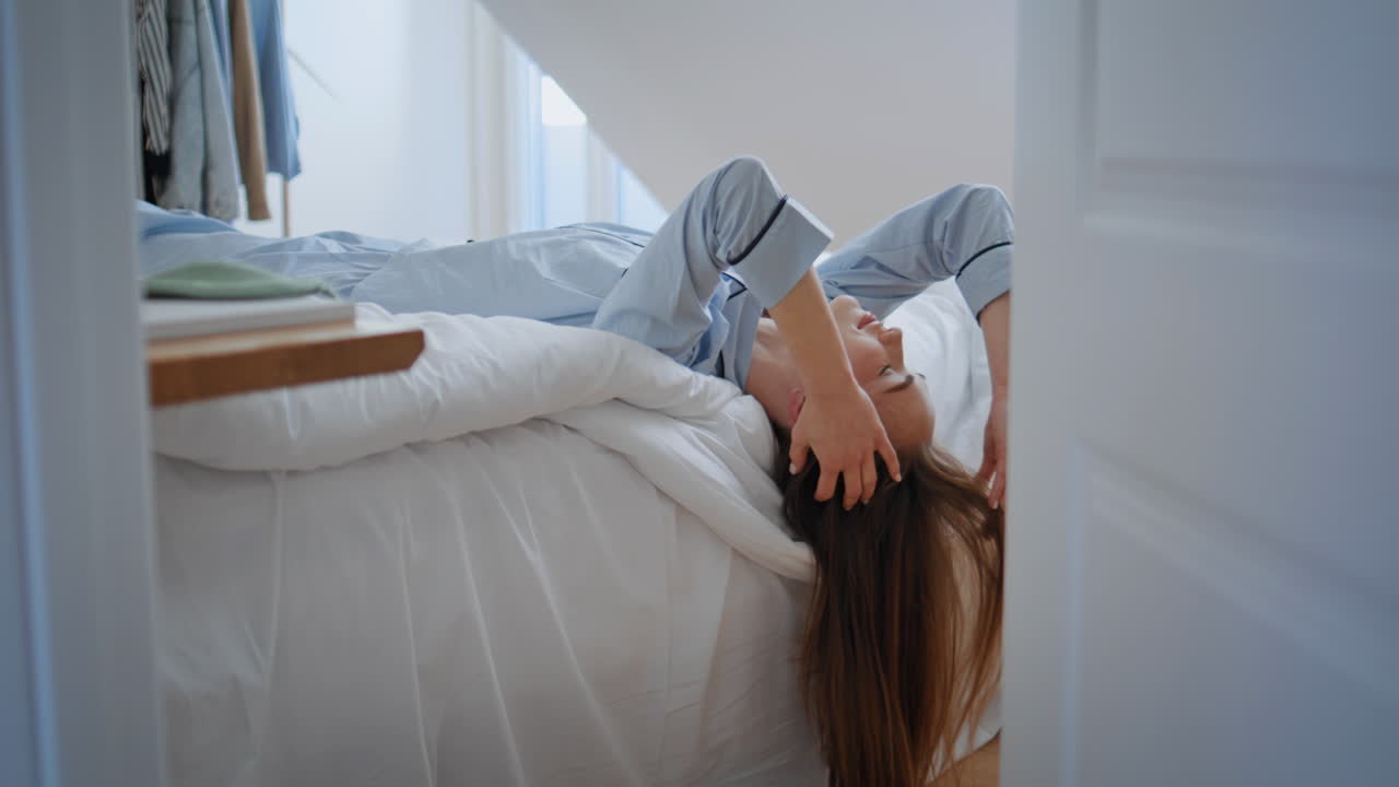 Drowsy model awaking bed closeup. Sleepy woman lying pillow touching hairstyle