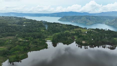 Backdrop-of-mist-covered-mountains,-foreground-of-still-calm-lake-water