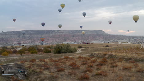 Coloridos-Globos-Aerostáticos-Volando-Sobre-El-Valle-Rojo-En-Capadocia,-Turquía-Al-Amanecer---Toma-Aérea-De-Drones