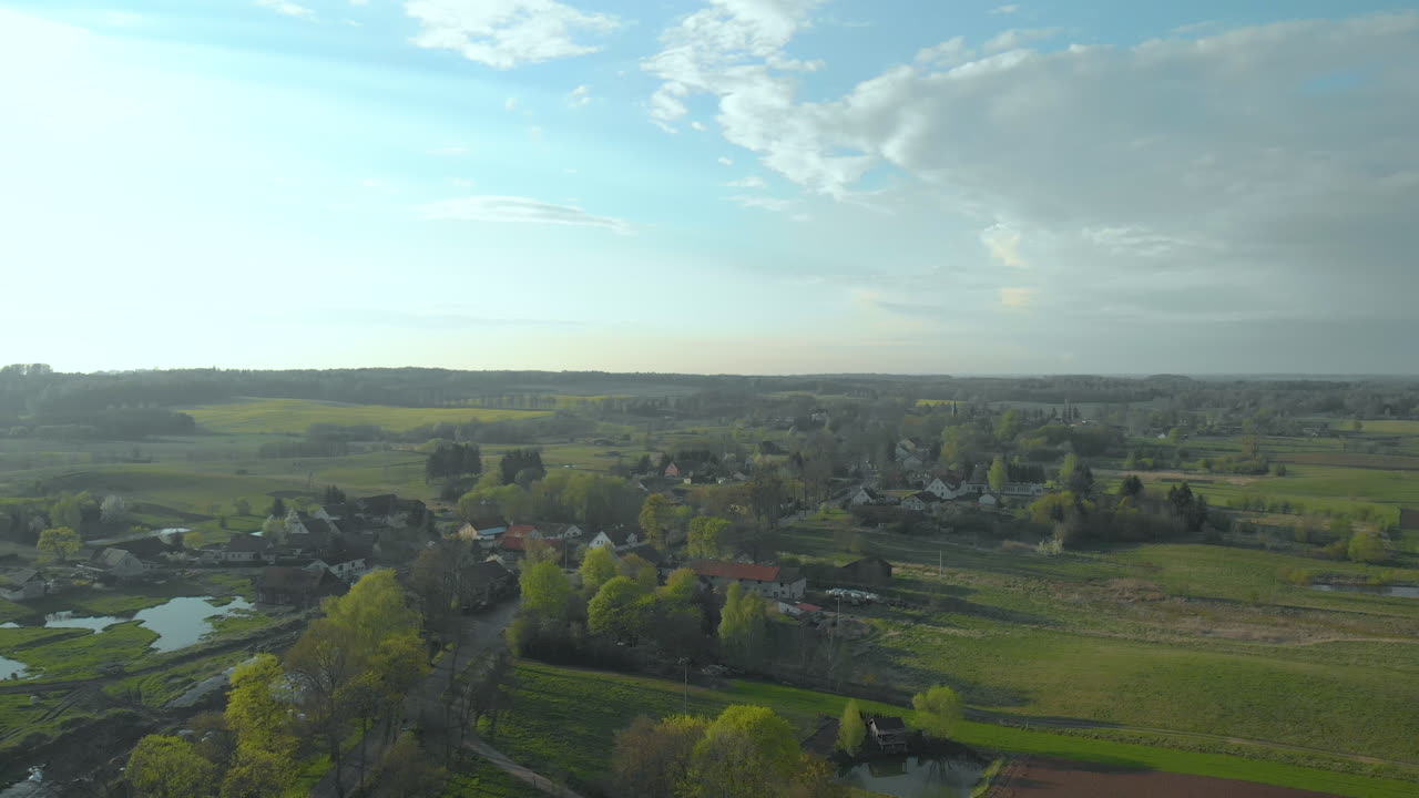 Aerial Over Local Village In Countryside With Blue Skies And Clouds. Follow Shot