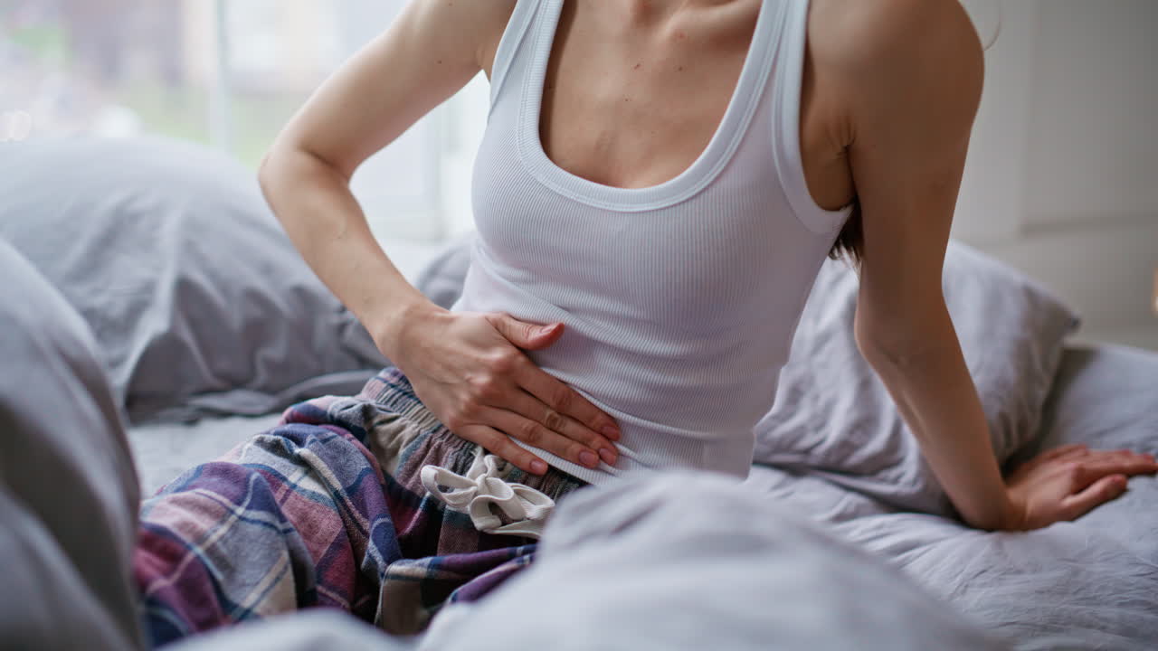 Suffering woman feeling belly ache menstrual spasm waking up in morning closeup