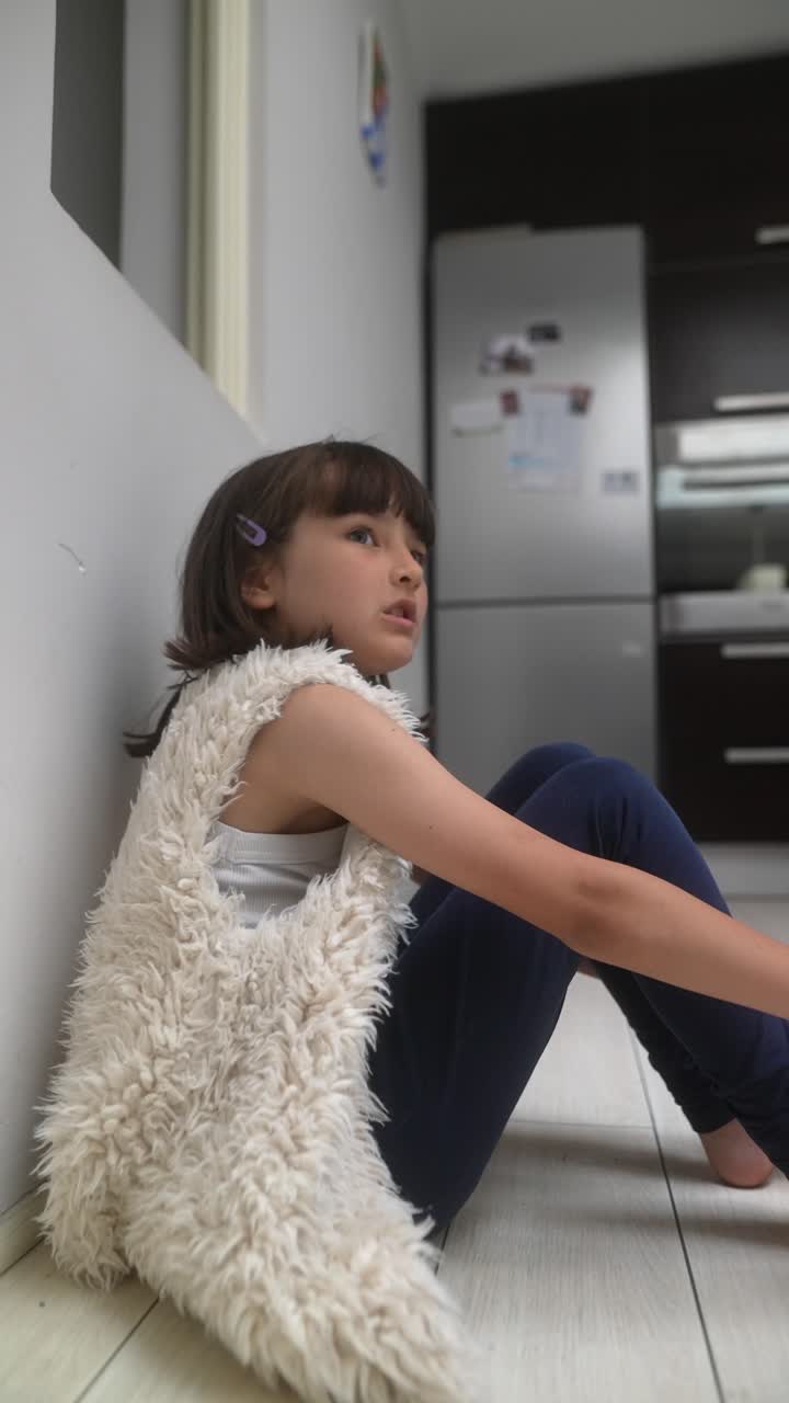 Young Girl Sitting on the Floor in a Kitchen