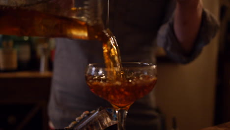 bartender pours manhattan cocktail to serve at bar, mixology dive bar
