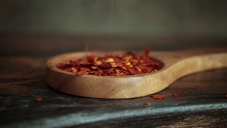 Flocken-Roter-Chilischote-In-Holzlöffel-Nahaufnahme-Auf-Einem-Küchentisch.