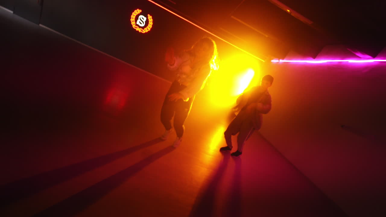 Pair dancing of hip hop. Young diverse dancers performing modern dance style in the studio with pink light.