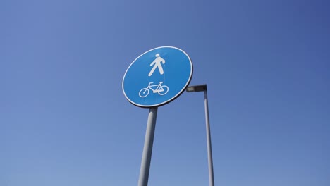 blue road sign pedestrian and cycle path against blue sky