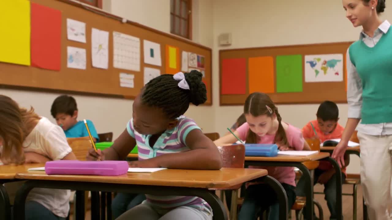 Jovem e bonita professora supervisionando seus pequenos alunos