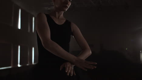 close-up of ballet dancer as she practices exercises on dark stage or studio. ballerina shows classic ballet pas. slow motion. flare gimbal shot.