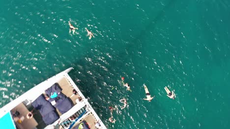 people jumping from catamaran and swimming in the ocean