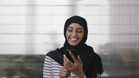 portrait-of-young-muslim-business-woman-laughing-cheerful-enjoying-watching-video-using-smartphone-in-office-background-fun-at-work