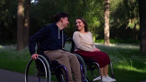 young couple in wheelchairs smiling in a park