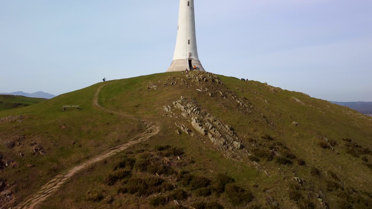 дрон поднимается, чтобы открыть памятник сэру джону барроу на вершине пышного холма, обрамленного чистым голубым небом.